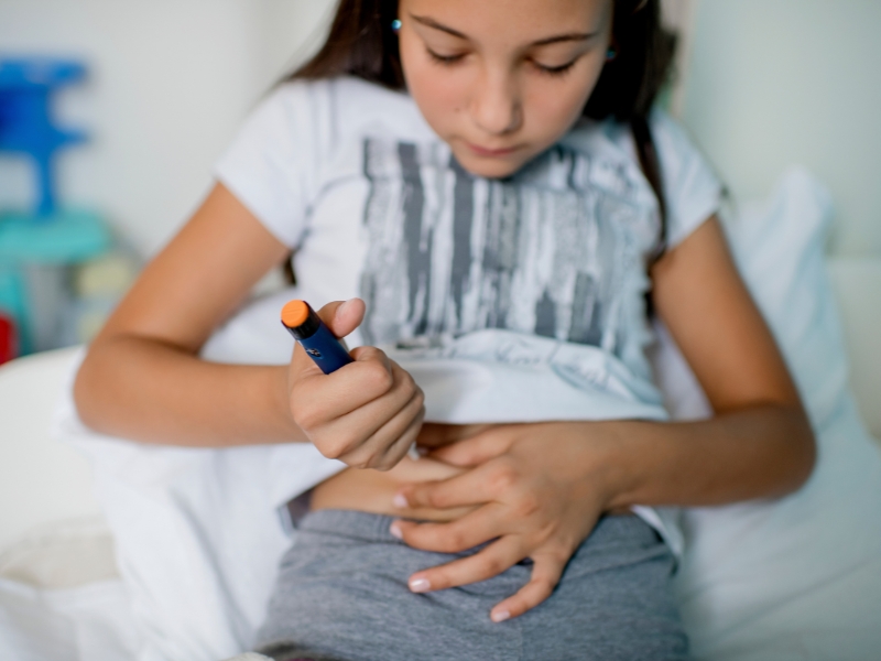 Barn med diabetes tar insulinspruta i magen